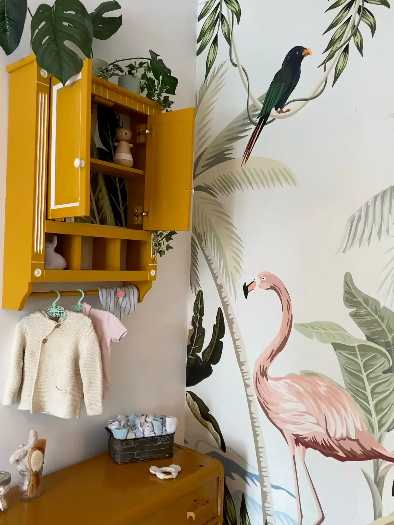 Chambre enfant décorée par Studio Pacha Montréal : meuble bois revalorisé blanc et jaune moutarde, papier peint jungle présentant un flamant rose