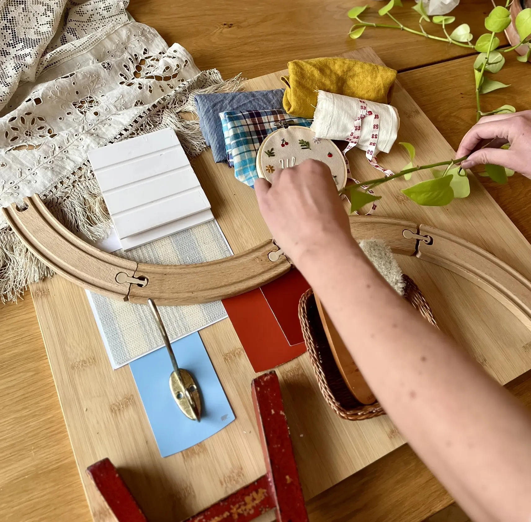 Mains de designer d'intérieur arrangeant une planche d’échantillons Studio Pacha : matériaux naturels, textures douces et couleurs pensées pour les espaces d’enfants